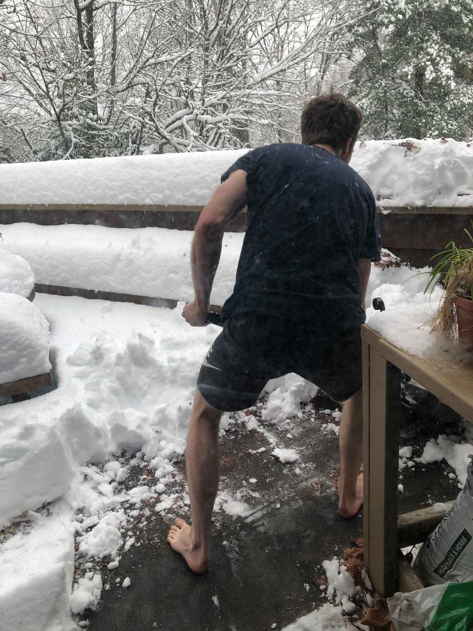Shoveling snow barefoot in shorts and a t-shirt